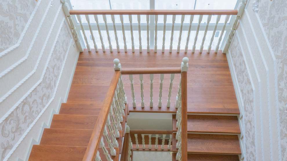 Пример оригинального дизайна: большая п-образная деревянная лестница в классическом стиле с деревянными ступенями, деревянными перилами и кирпичными стенами