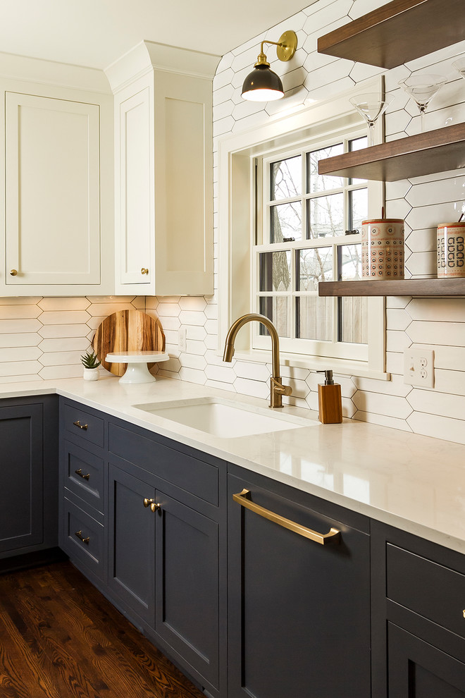 This is an example of a mid-sized transitional l-shaped kitchen in Minneapolis with an undermount sink, shaker cabinets, white cabinets, quartz benchtops, white splashback, ceramic splashback, panelled appliances, dark hardwood floors, no island and brown floor.