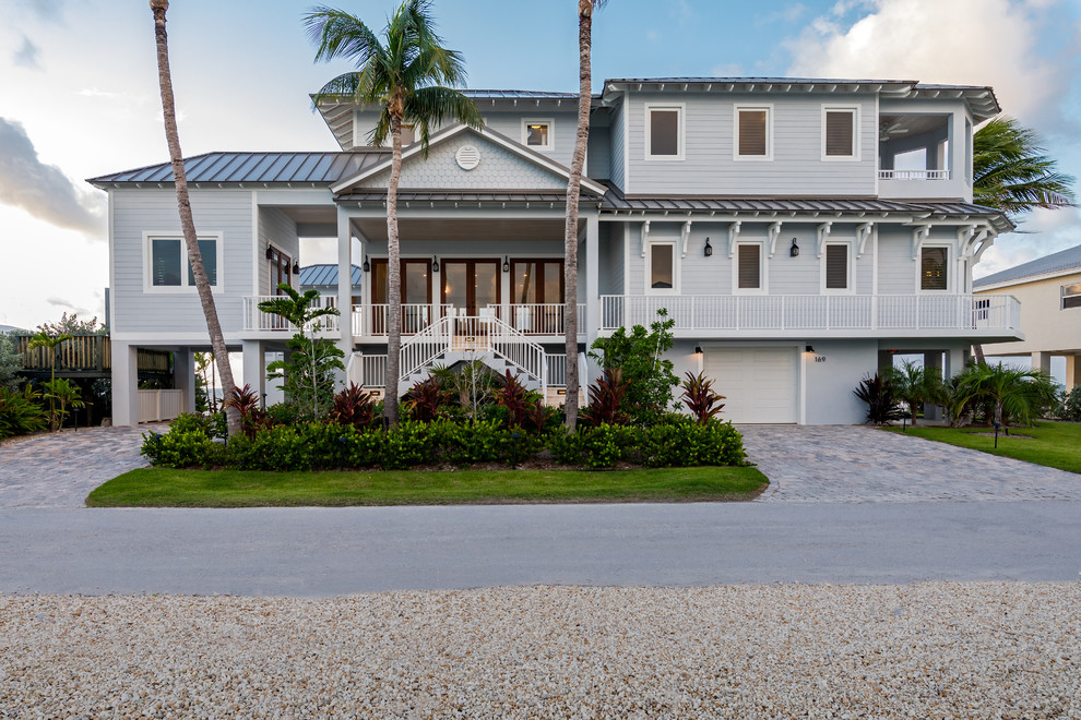 Photo of a large beach style three-storey grey house exterior in Miami with a hip roof and a metal roof.