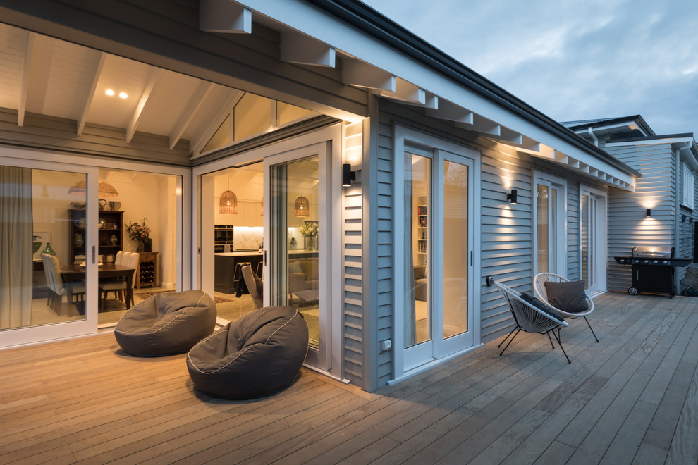 Large contemporary backyard deck in Auckland with with dock and a roof extension.