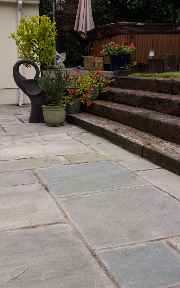 This is an example of a mid-sized traditional courtyard patio in Hampshire with natural stone pavers.
