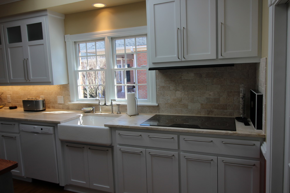 Inspiration for a mid-sized transitional u-shaped medium tone wood floor eat-in kitchen remodel with a farmhouse sink, shaker cabinets, yellow cabinets, marble countertops, beige backsplash, stone tile backsplash, stainless steel appliances and an island