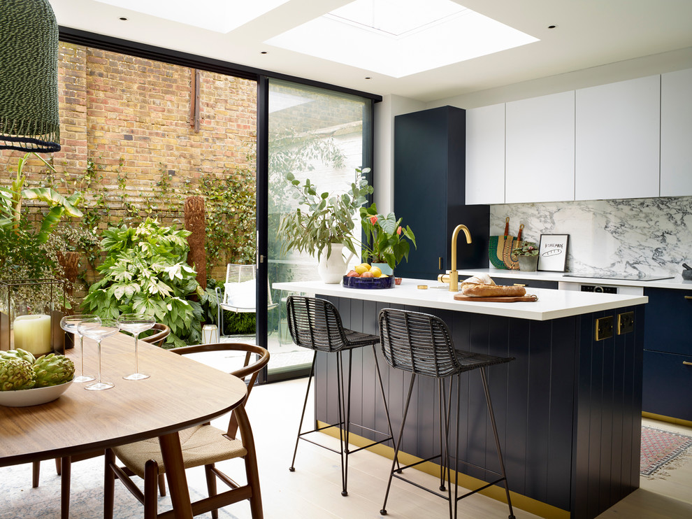 Mid-sized contemporary eat-in kitchen in London with flat-panel cabinets, blue cabinets, light hardwood floors, with island, beige floor and white benchtop.