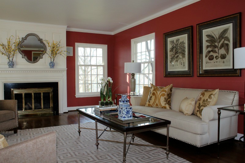 Photo of a large traditional formal enclosed living room in Kansas City with red walls, dark hardwood floors, a standard fireplace, a wood fireplace surround and no tv.
