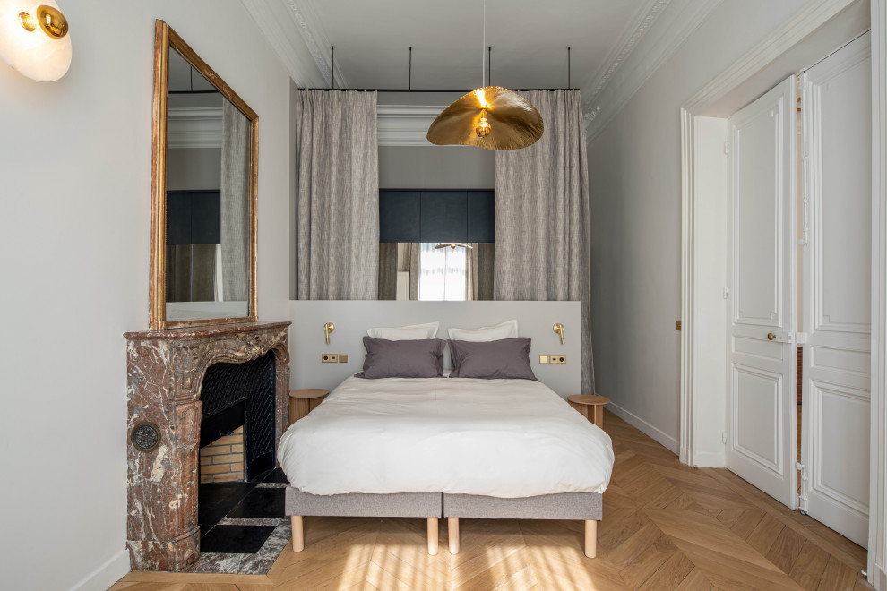 Réalisation d'une chambre parentale design avec une cheminée standard, un manteau de cheminée en pierre et dressing.