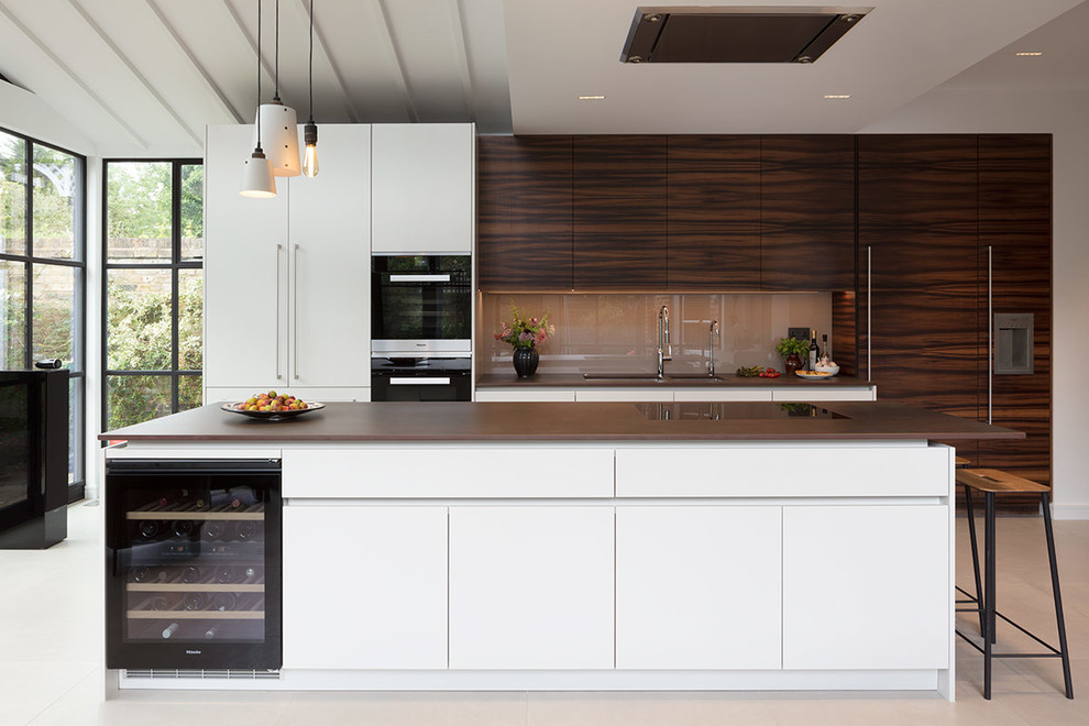 Inspiration for a contemporary kitchen in London with an undermount sink, flat-panel cabinets, dark wood cabinets, brown splashback, glass sheet splashback, panelled appliances, with island, grey floor and brown benchtop.