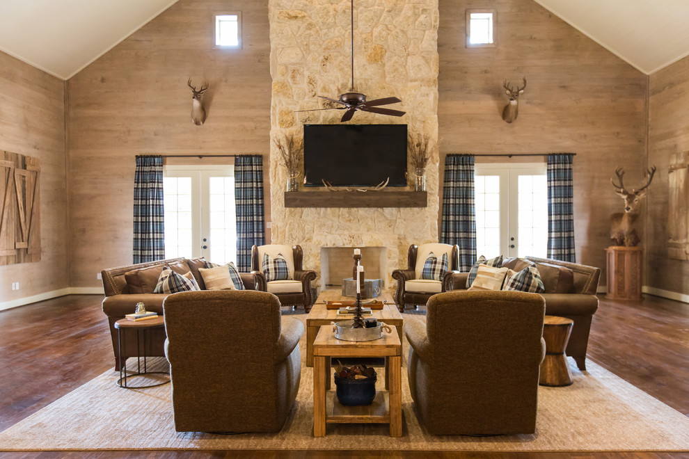 Family room - large rustic open concept medium tone wood floor and brown floor family room idea in Houston with a standard fireplace, a stone fireplace, a wall-mounted tv and beige walls