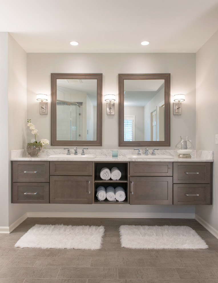 This is an example of a large transitional master bathroom in Kansas City with shaker cabinets, dark wood cabinets, gray tile, grey walls, porcelain floors, granite benchtops, grey floor, white benchtops and a drop-in sink.