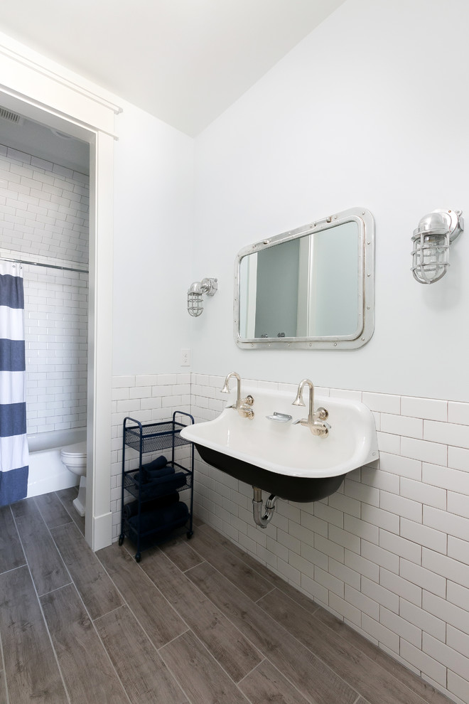 Photo of a mid-sized country kids bathroom in Charleston with open cabinets, an alcove tub, a shower/bathtub combo, a two-piece toilet, white tile, subway tile, white walls, porcelain floors, an integrated sink, grey floor and a shower curtain.