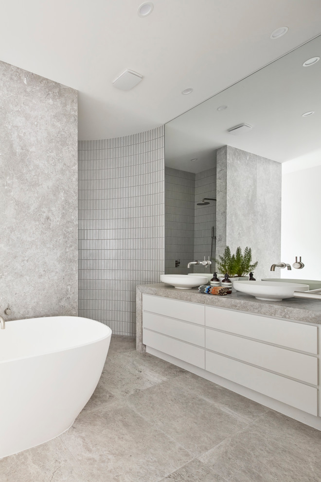 Contemporary master bathroom in Melbourne with flat-panel cabinets, beige cabinets, a freestanding tub, gray tile, marble, grey walls, a vessel sink and beige floor.