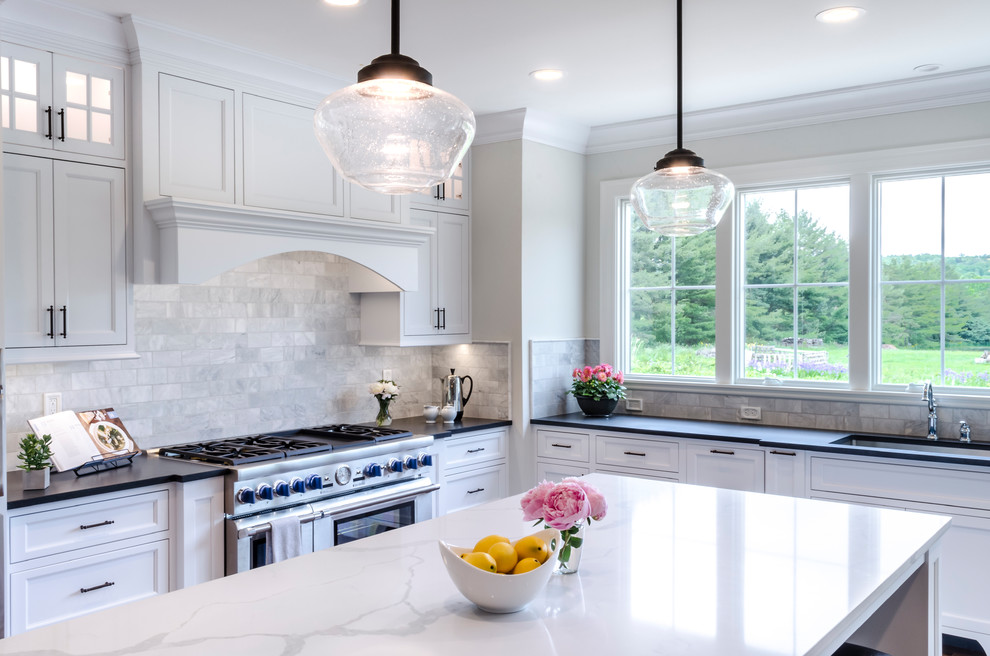 Inspiration for a large traditional kitchen in Cleveland with shaker cabinets, grey splashback, subway tile splashback, stainless steel appliances, medium hardwood floors, with island, brown floor, an undermount sink and white cabinets.