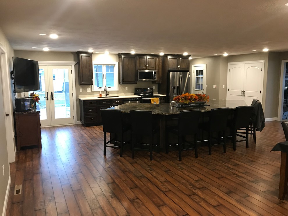 Large elegant galley dark wood floor and brown floor open concept kitchen photo with raised-panel cabinets, granite countertops, stainless steel appliances, an undermount sink, dark wood cabinets and an island