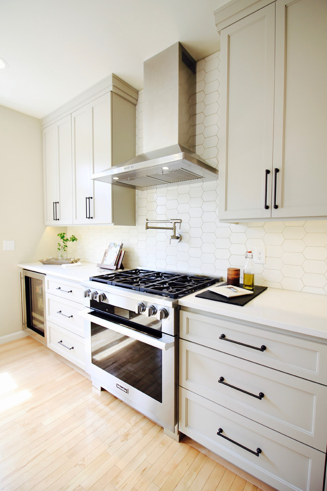 Eat-in kitchen - large transitional l-shaped light wood floor eat-in kitchen idea in Seattle with a farmhouse sink, shaker cabinets, gray cabinets, quartz countertops, white backsplash, porcelain backsplash, stainless steel appliances and an island
