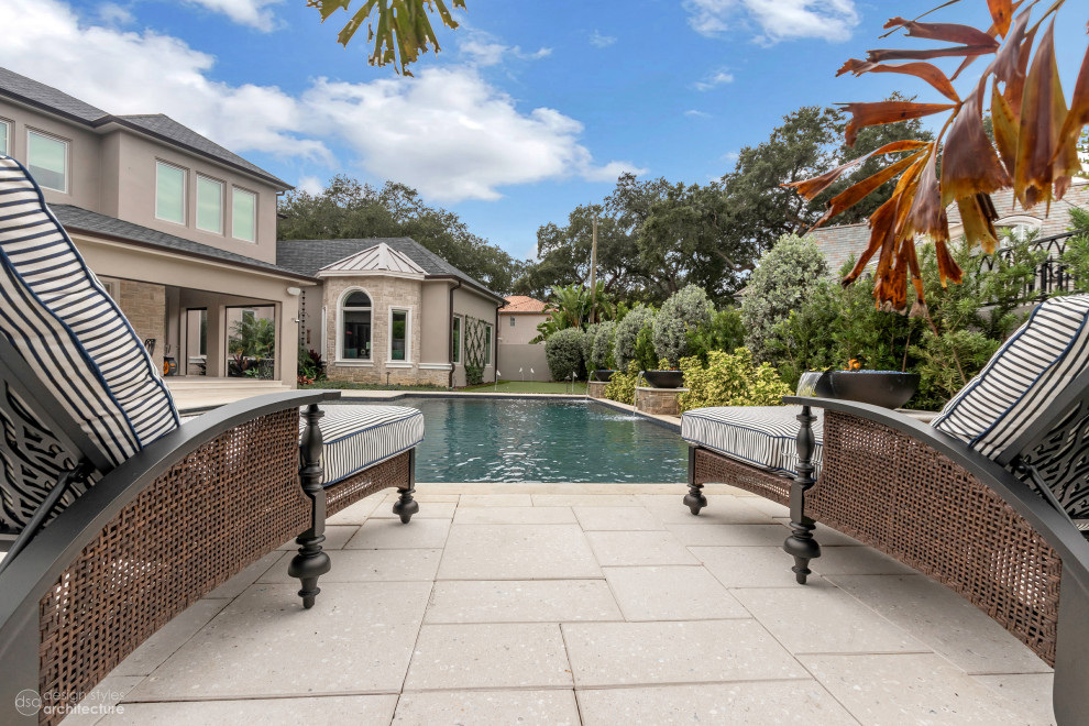 Design ideas for a large traditional backyard custom-shaped lap pool in Tampa with a water feature and concrete pavers.