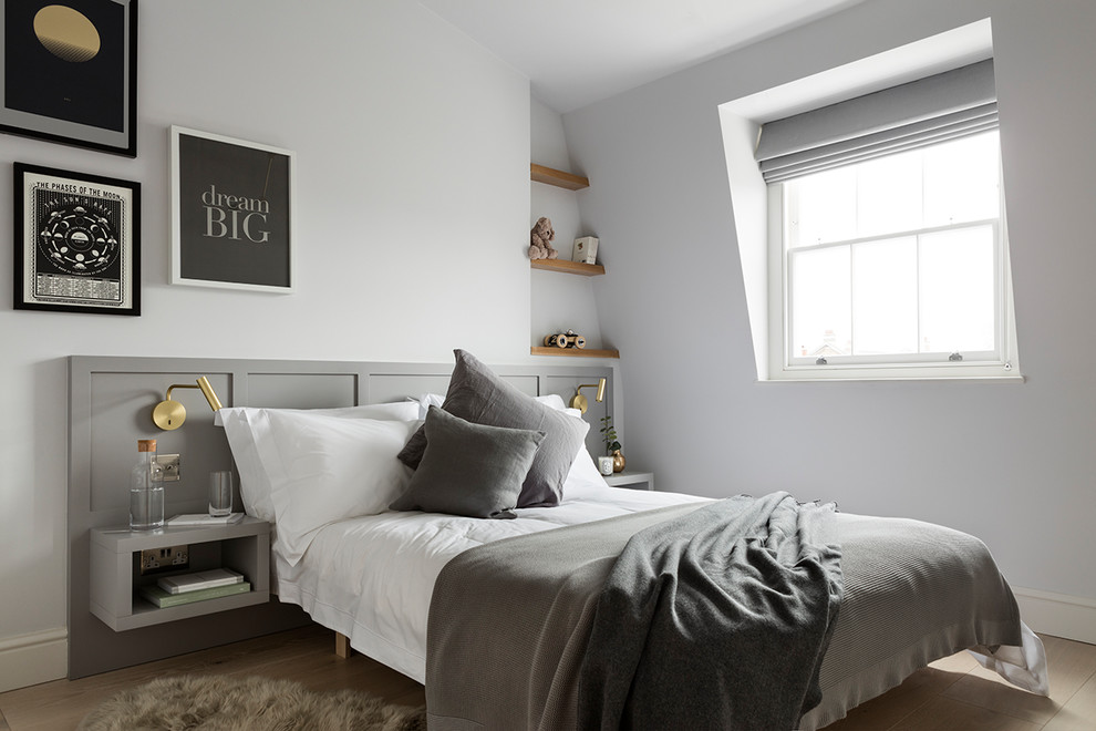 Photo of a mid-sized scandinavian gender-neutral kids' room in London with white walls, light hardwood floors and beige floor.