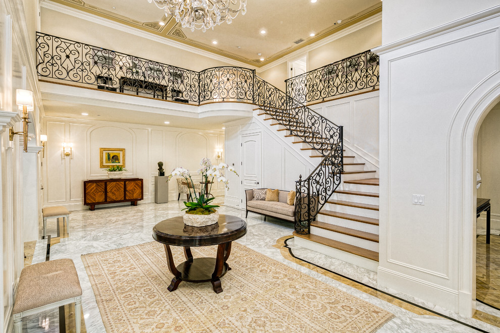 This is an example of a traditional foyer in Los Angeles with white walls, marble floors, a single front door, a medium wood front door and multi-coloured floor.