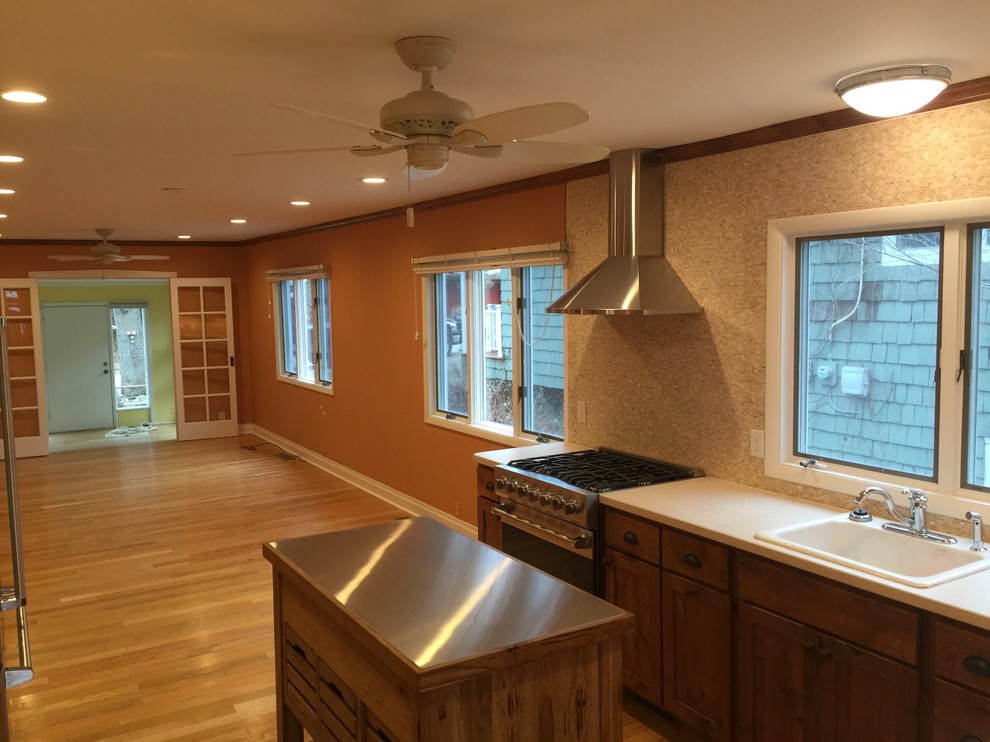 This is an example of a small traditional l-shaped eat-in kitchen in Orange County with flat-panel cabinets, dark wood cabinets, mosaic tile splashback, stainless steel appliances, medium hardwood floors and with island.