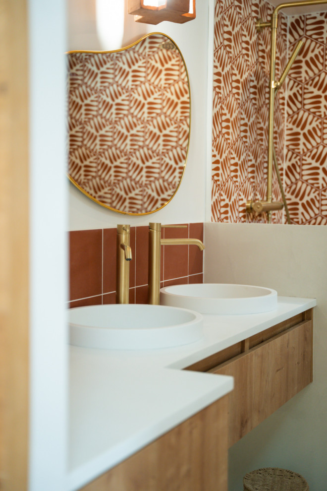 Minimalistisk inredning av ett litet vit vitt badrum med dusch, med luckor med profilerade fronter, skåp i ljust trä, en kantlös dusch, röd kakel, vita väggar och ett undermonterad handfat