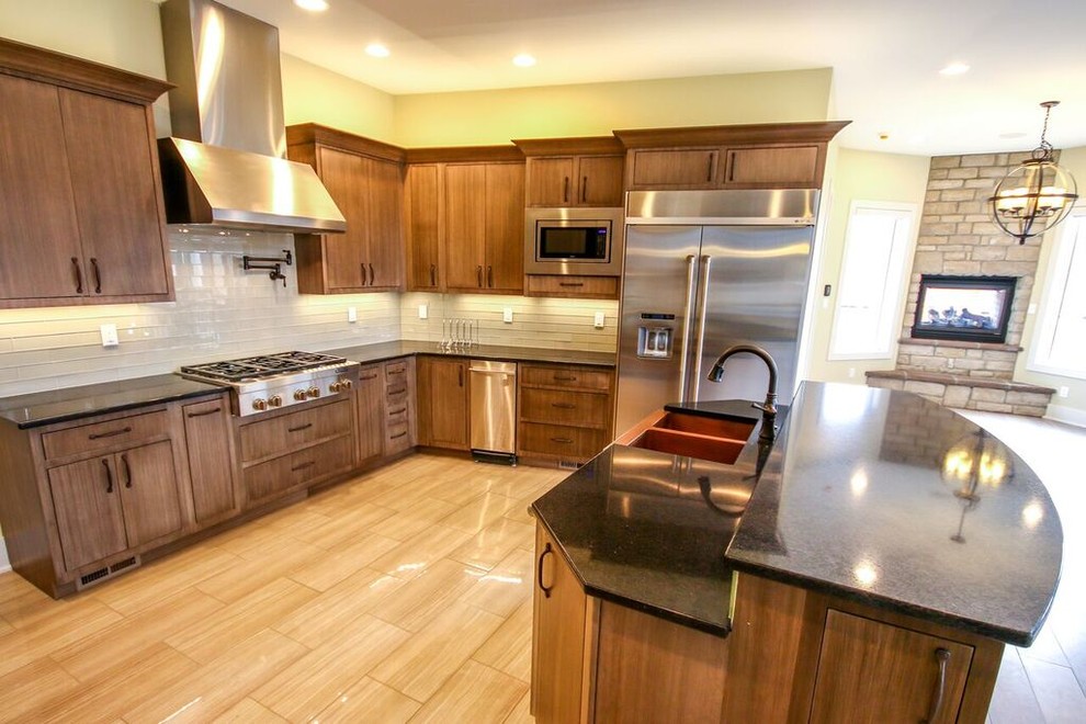 Mid-sized transitional u-shaped light wood floor eat-in kitchen photo with a farmhouse sink, flat-panel cabinets, dark wood cabinets, solid surface countertops, yellow backsplash, subway tile backsplash, stainless steel appliances and no island