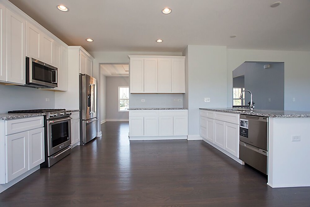 Example of a large transitional single-wall dark wood floor and brown floor kitchen design in Chicago with an undermount sink, recessed-panel cabinets, white cabinets, granite countertops, stainless steel appliances and no island