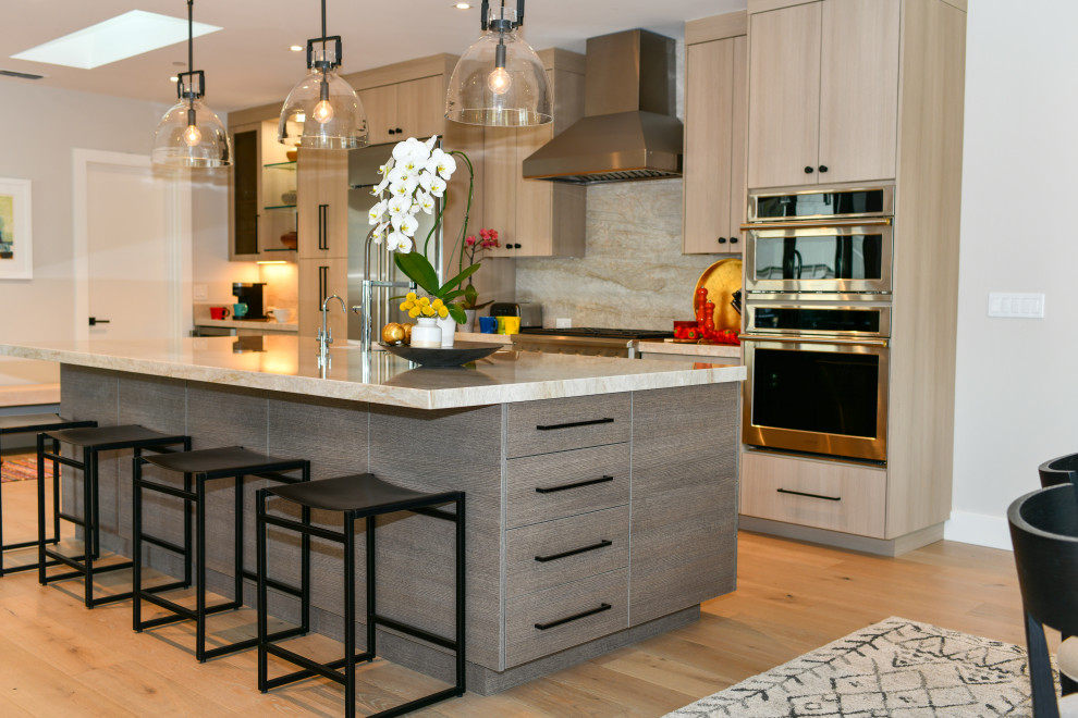 Huge transitional galley light wood floor and beige floor open concept kitchen photo in San Francisco with a drop-in sink, flat-panel cabinets, gray cabinets, quartzite countertops, white backsplash, marble backsplash, stainless steel appliances, an island and white countertops