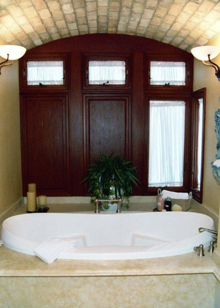 Photo of a large country master bathroom in Orange County with a drop-in sink, recessed-panel cabinets, medium wood cabinets, limestone benchtops, a curbless shower, stone tile, limestone floors and a drop-in tub.