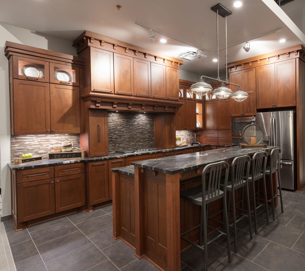 This is an example of a mid-sized transitional l-shaped open plan kitchen in Austin with an undermount sink, shaker cabinets, medium wood cabinets, marble benchtops, grey splashback, matchstick tile splashback, stainless steel appliances, porcelain floors, with island, grey floor and black benchtop.