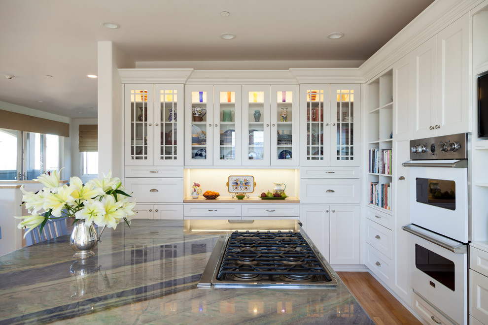 Inspiration for a large transitional eat-in kitchen in Los Angeles with an undermount sink, recessed-panel cabinets, white cabinets, quartzite benchtops, grey splashback, stone slab splashback, panelled appliances, light hardwood floors and with island.