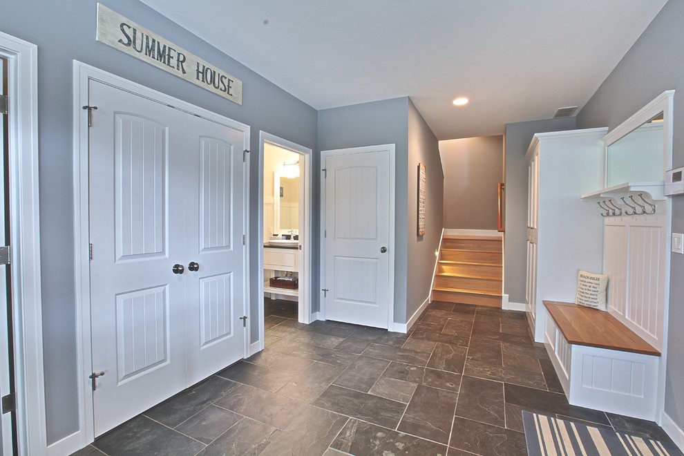 This is an example of a beach style mudroom in Grand Rapids with blue walls, slate floors, a single front door and a light wood front door.