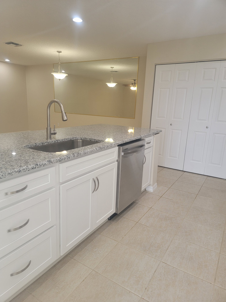 Example of a mid-sized galley eat-in kitchen design with an undermount sink, shaker cabinets, white cabinets, quartz countertops, a peninsula and gray countertops