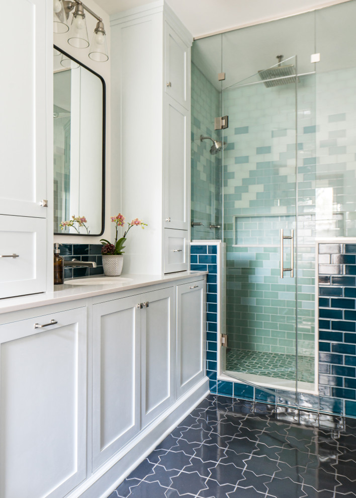 Пример оригинального дизайна: главная ванная комната среднего размера в стиле неоклассика (современная классика) с фасадами с декоративным кантом, белыми фасадами, отдельно стоящей ванной, двойным душем, унитазом-моноблоком, синей плиткой, керамической плиткой, белыми стенами, полом из керамической плитки, врезной раковиной, столешницей из искусственного кварца, серым полом, душем с распашными дверями, белой столешницей, сиденьем для душа, тумбой под одну раковину, встроенной тумбой и панелями на стенах