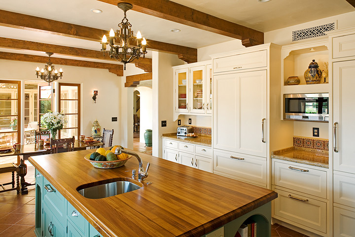 Design ideas for a large country u-shaped eat-in kitchen in San Diego with recessed-panel cabinets, white cabinets, wood benchtops, multi-coloured splashback, terra-cotta splashback, panelled appliances, porcelain floors and with island.