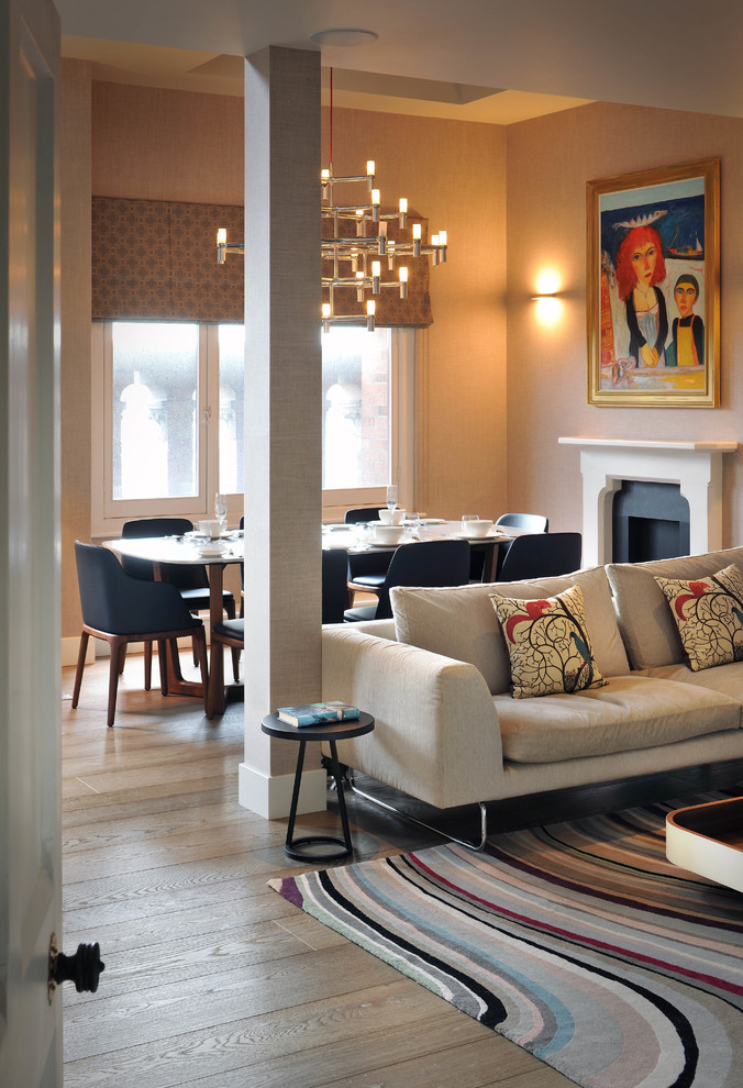 Mid-sized contemporary dining room in London with beige walls, medium hardwood floors and a standard fireplace.