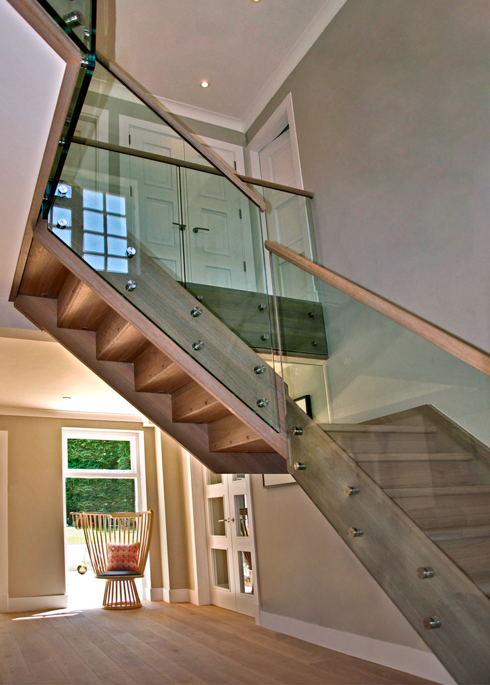 This is an example of a mid-sized country wood l-shaped staircase in Buckinghamshire with wood risers and glass railing.