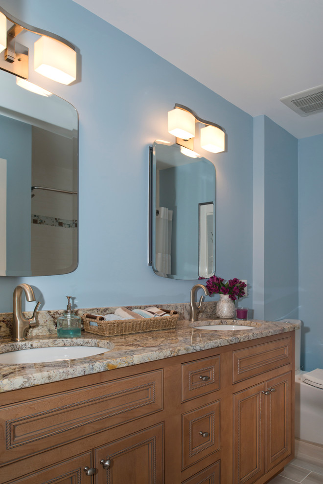 This is an example of a mid-sized contemporary bathroom in DC Metro with an undermount sink, beaded inset cabinets, light wood cabinets, granite benchtops, an alcove tub, a shower/bathtub combo, a one-piece toilet, white tile, porcelain tile, blue walls and porcelain floors.