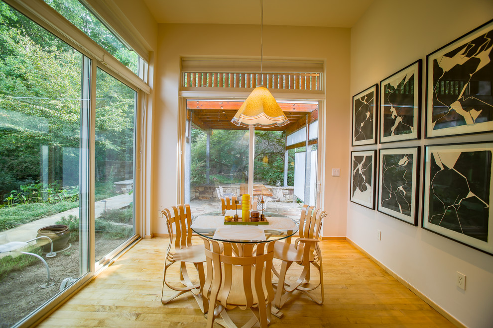 This is an example of a small contemporary open plan dining in Raleigh with beige walls, light hardwood floors and no fireplace.
