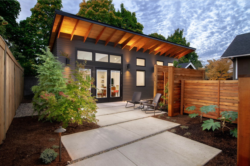 Immagine di un piccolo patio o portico minimal davanti casa con lastre di cemento e un tetto a sbalzo