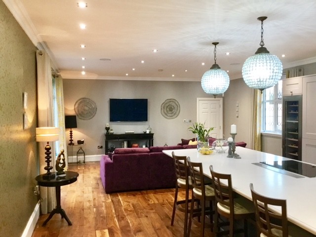 Photo of a large transitional u-shaped kitchen in Glasgow with a drop-in sink, shaker cabinets, grey cabinets, marble benchtops, white splashback, stone slab splashback, medium hardwood floors and with island.