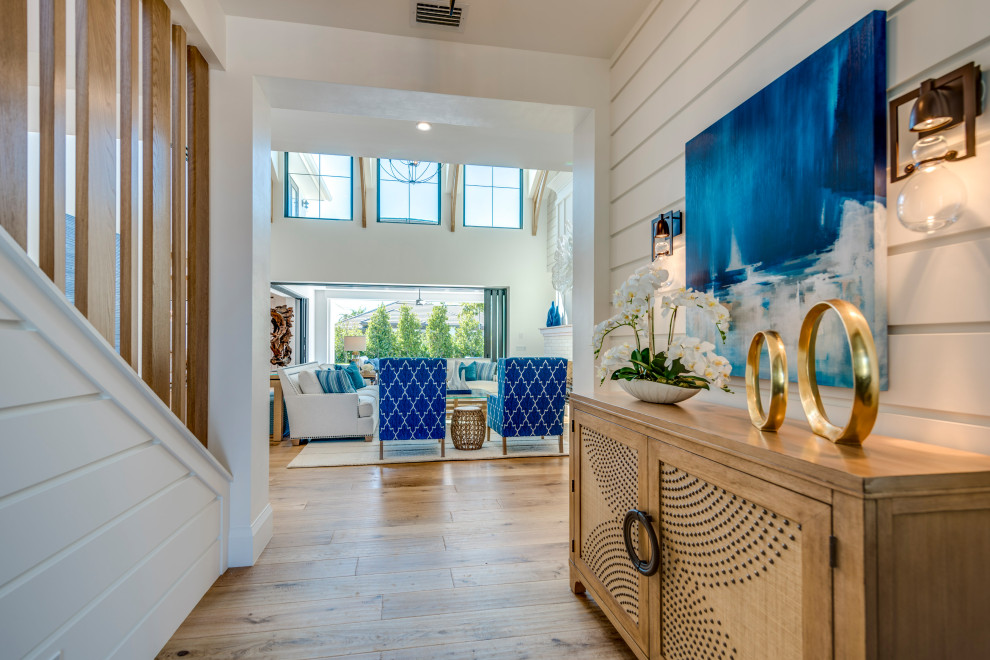 Design ideas for a large beach style foyer in Miami with white walls, medium hardwood floors, a double front door, a glass front door and brown floor.