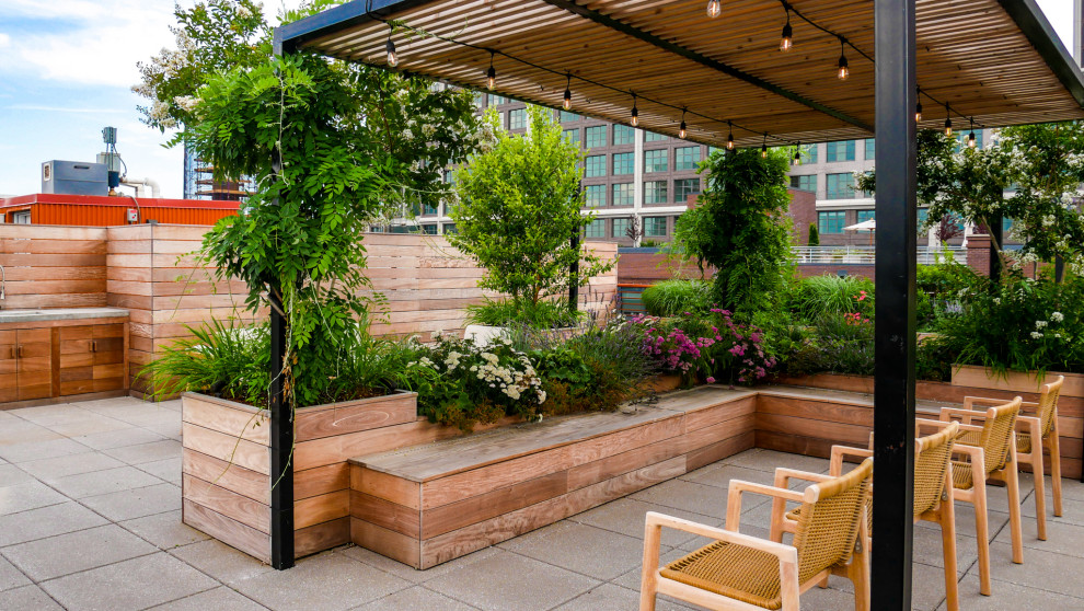 Photo of a large modern rooftop and rooftop deck in New York with an outdoor kitchen, a pergola and mixed railing.