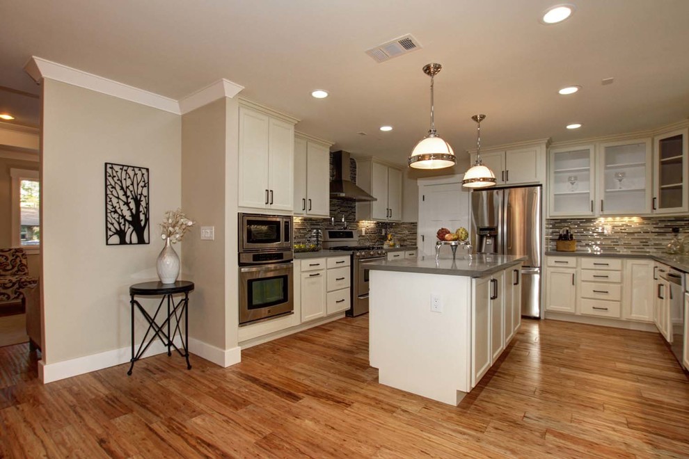 Kitchen - large traditional galley light wood floor kitchen idea in Austin with an undermount sink, recessed-panel cabinets, white cabinets, quartzite countertops, multicolored backsplash, mosaic tile backsplash, stainless steel appliances and an island