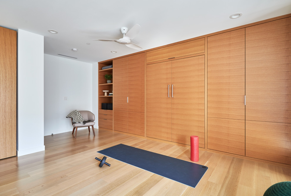 Mittelgroßer Moderner Fitnessraum mit weißer Wandfarbe und hellem Holzboden in Cincinnati