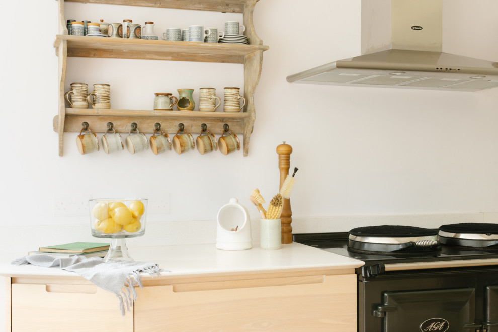 Inspiration for a medium sized contemporary u-shaped kitchen/diner with a built-in sink, flat-panel cabinets, light wood cabinets, soapstone worktops, black appliances, an island, beige floors and white worktops.