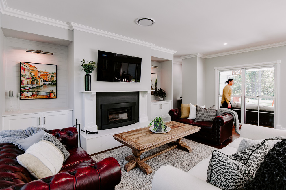 This is an example of a contemporary open concept living room in Sunshine Coast with grey walls, dark hardwood floors, a wood stove, a metal fireplace surround, a wall-mounted tv and brown floor.