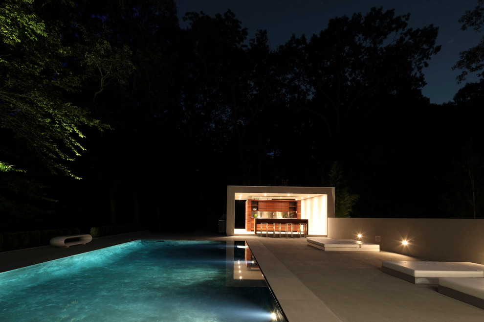 Large modern backyard rectangular infinity pool in New York with concrete slab.