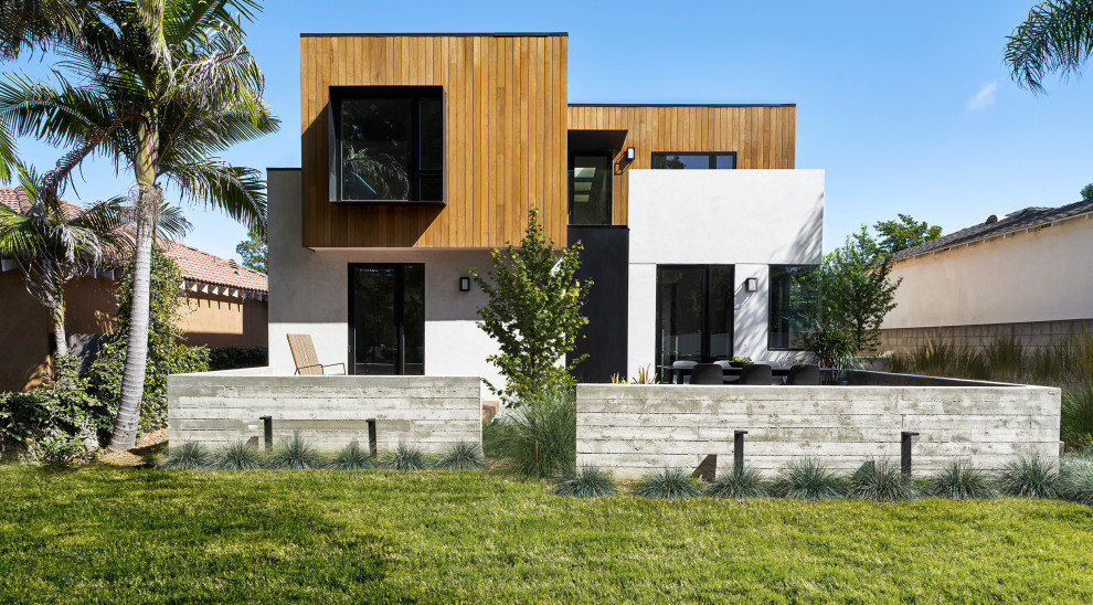 Example of a mid-sized trendy white two-story wood exterior home design in Los Angeles with a mixed material roof