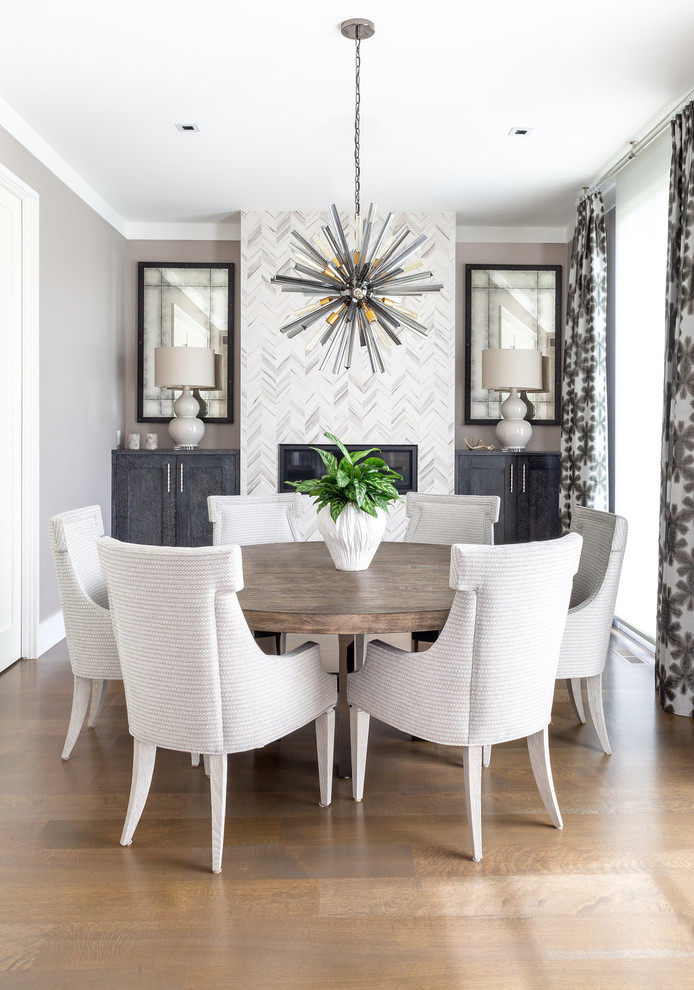This is an example of a contemporary dining room in Chicago with grey walls, medium hardwood floors, a ribbon fireplace and a tile fireplace surround.