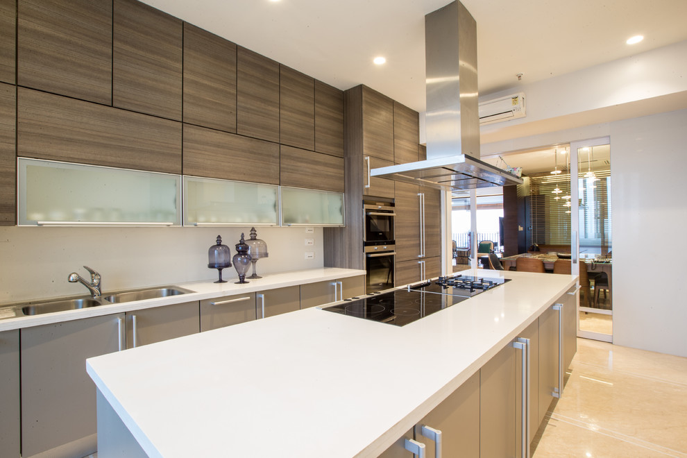 Photo of a mid-sized contemporary galley kitchen in Hyderabad with flat-panel cabinets, beige cabinets, solid surface benchtops, stainless steel appliances and with island.
