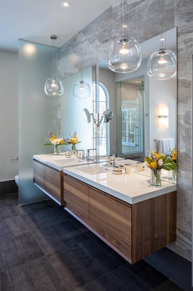 Large contemporary master bathroom in Ottawa with flat-panel cabinets, medium wood cabinets, a freestanding tub, an alcove shower, gray tile, porcelain tile, white walls, porcelain floors, an integrated sink, engineered quartz benchtops and grey floor.