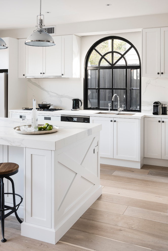 Design ideas for a large industrial galley open plan kitchen in Melbourne with a double-bowl sink, recessed-panel cabinets, white cabinets, quartz benchtops, white splashback, marble splashback, white appliances, medium hardwood floors, with island and grey floor.